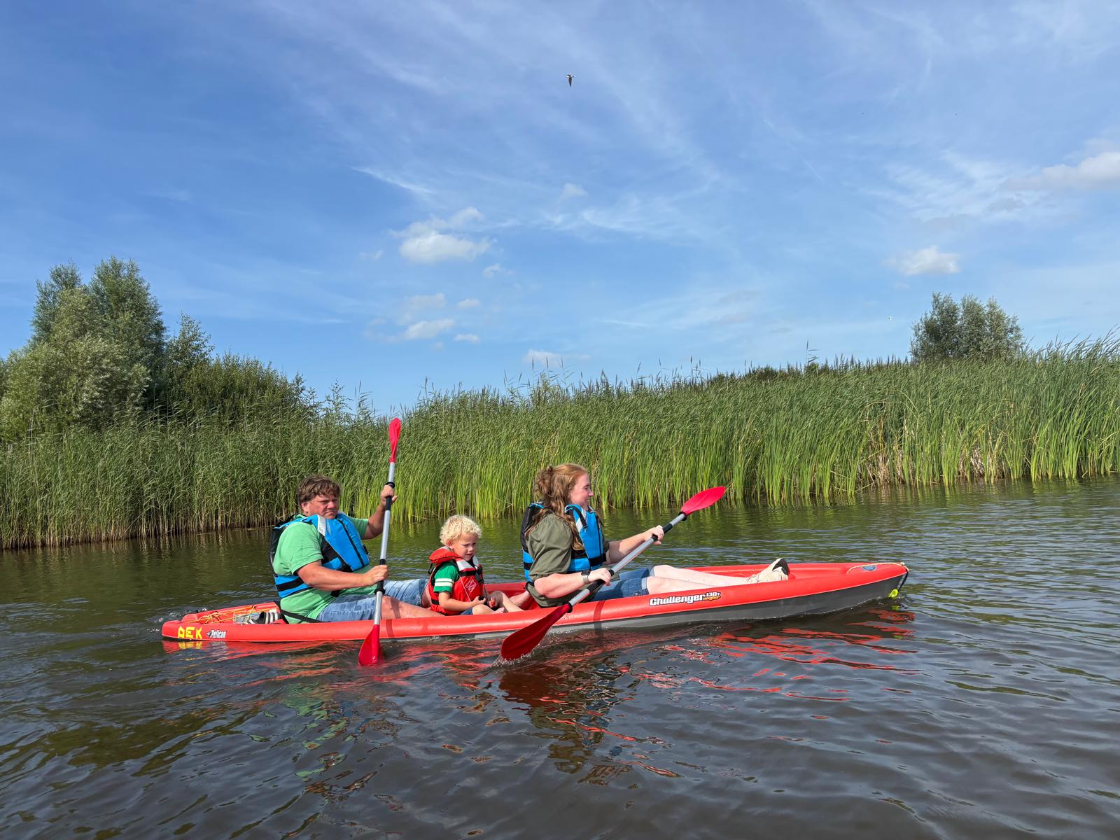 Twee volwassenen met een kind in een duo-kayak bij DEK Blauwestad